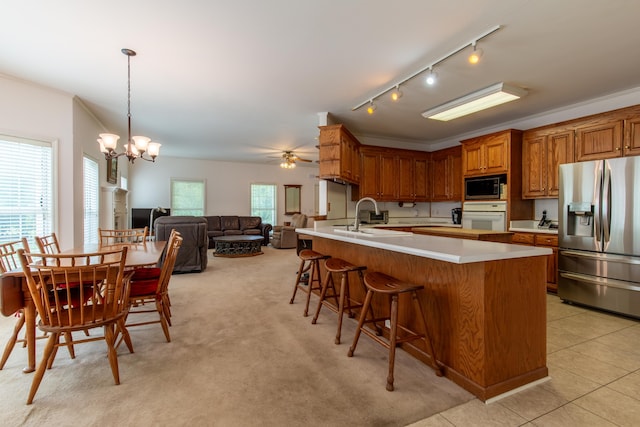 kitchen featuring crown molding, rail lighting, ceiling fan with notable chandelier, hanging light fixtures, and appliances with stainless steel finishes