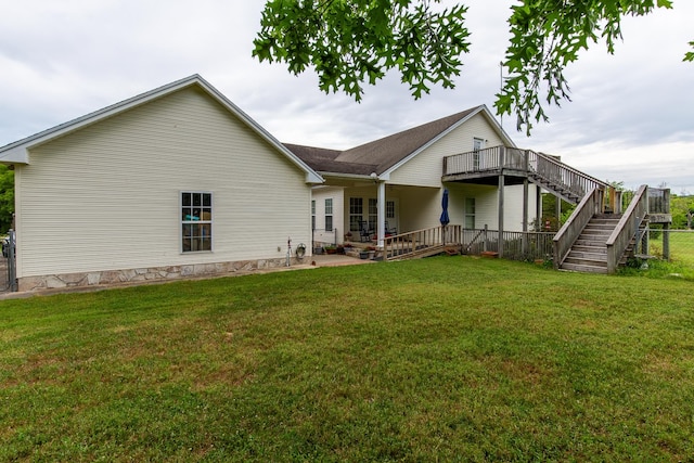 rear view of house featuring a wooden deck and a yard