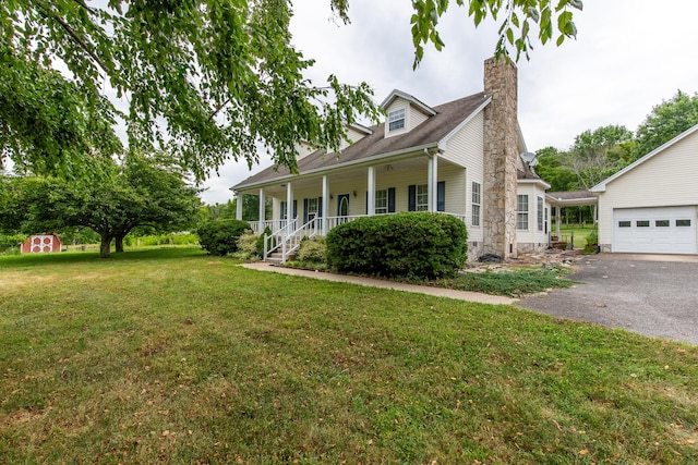 view of side of property with a garage, a yard, an outbuilding, and covered porch