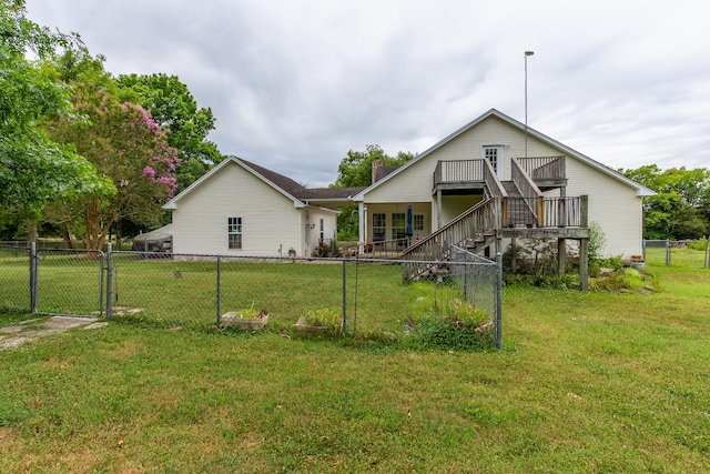 rear view of property featuring a wooden deck and a lawn