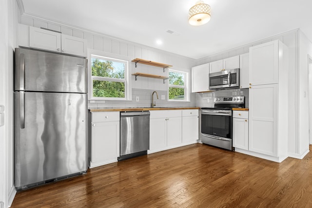 kitchen featuring appliances with stainless steel finishes, dark wood-type flooring, tasteful backsplash, and white cabinetry