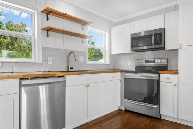 kitchen featuring appliances with stainless steel finishes, white cabinetry, dark hardwood / wood-style flooring, crown molding, and sink