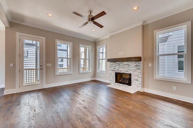 unfurnished living room with a stone fireplace, dark wood-type flooring, ceiling fan, and crown molding