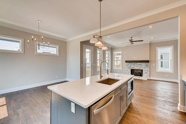 kitchen with a fireplace, dark hardwood / wood-style floors, stainless steel appliances, and a kitchen island with sink