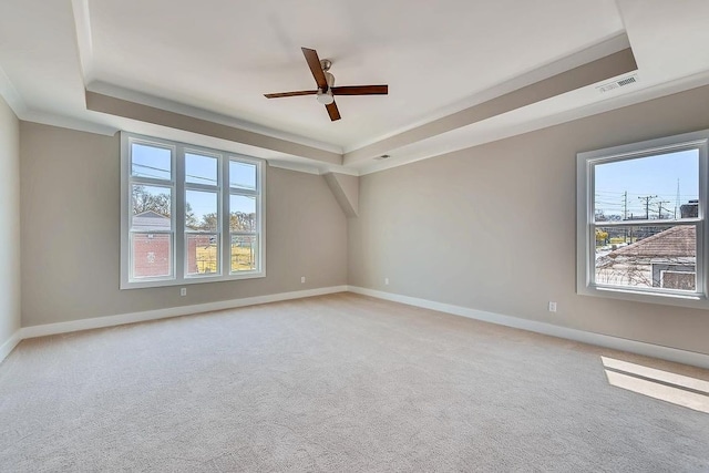 empty room with light carpet, ceiling fan, and a raised ceiling