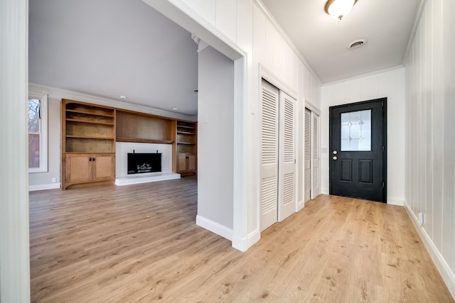 doorway to outside featuring ornamental molding, built in features, and light wood-type flooring