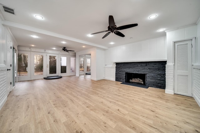 unfurnished living room featuring crown molding, a stone fireplace, ceiling fan, and light hardwood / wood-style flooring