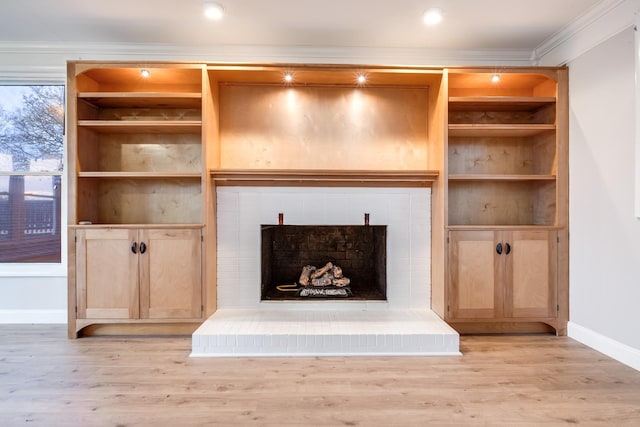 unfurnished living room with ornamental molding, light hardwood / wood-style floors, and a brick fireplace