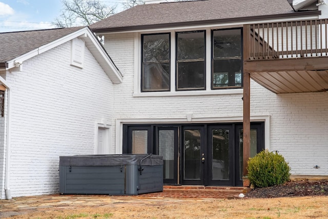 rear view of house featuring a hot tub and a balcony