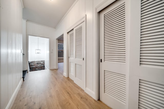 corridor featuring ornamental molding and light hardwood / wood-style floors