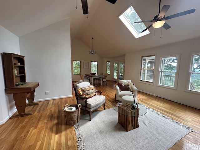 living room with a skylight, a wealth of natural light, light wood-type flooring, and ceiling fan