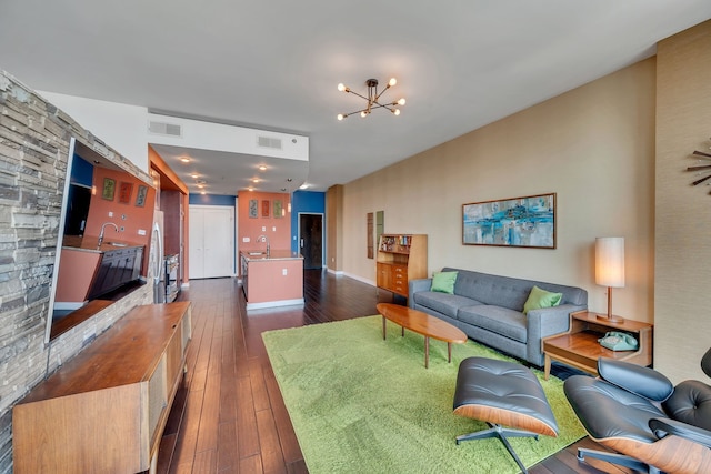 living room with sink, an inviting chandelier, and dark wood-type flooring