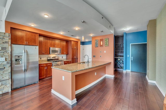 kitchen with appliances with stainless steel finishes, sink, hanging light fixtures, backsplash, and dark hardwood / wood-style flooring