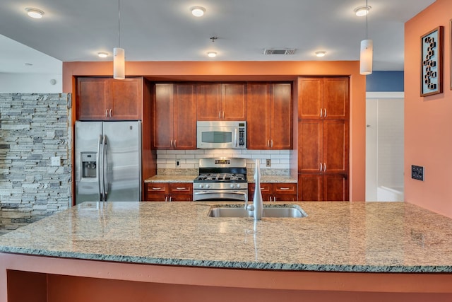 kitchen featuring light stone counters, tasteful backsplash, stainless steel appliances, and decorative light fixtures