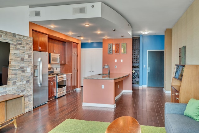 kitchen with appliances with stainless steel finishes, light stone counters, sink, and dark wood-type flooring