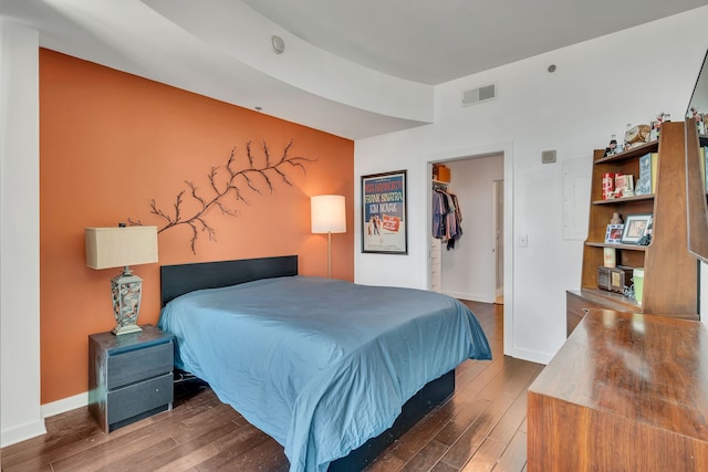 bedroom featuring a spacious closet, a closet, and wood-type flooring