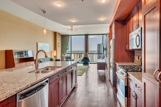 kitchen featuring light stone countertops, hanging light fixtures, appliances with stainless steel finishes, and sink