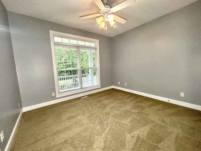 spare room featuring baseboards, visible vents, dark carpet, and a ceiling fan
