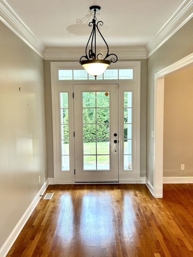 doorway featuring baseboards, visible vents, ornamental molding, and wood finished floors
