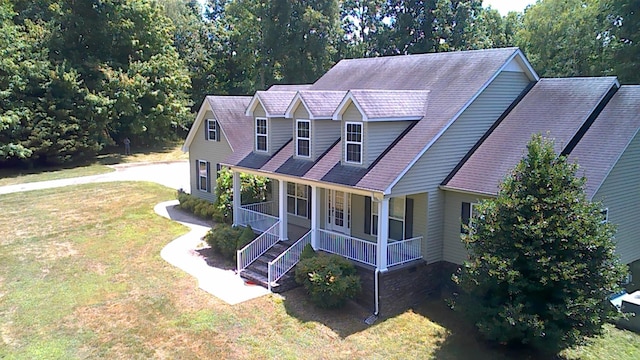 new england style home featuring a porch and a front lawn