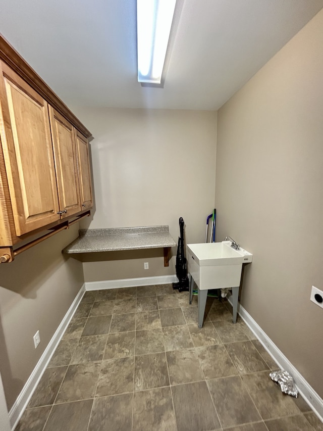 laundry area featuring cabinets, hookup for an electric dryer, and dark tile patterned flooring