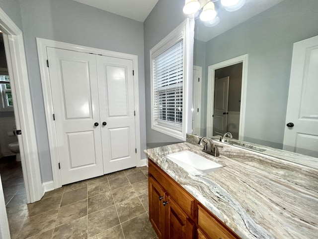 bathroom with toilet, baseboards, and vanity