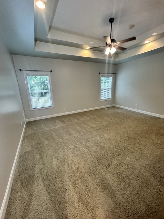 unfurnished room with carpet flooring, ceiling fan, and a raised ceiling