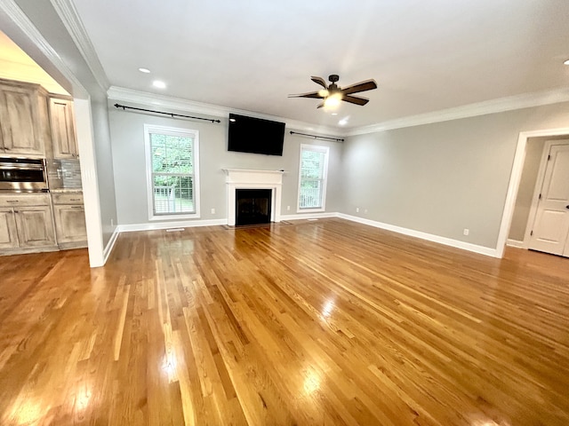 unfurnished living room featuring ornamental molding, ceiling fan, and light wood-type flooring