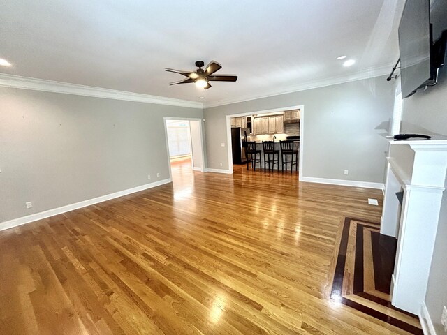 unfurnished living room featuring ornamental molding, light wood-type flooring, and ceiling fan