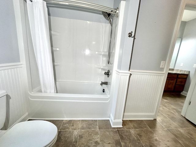 bathroom with a wainscoted wall, vanity, shower / bath combination with curtain, and toilet