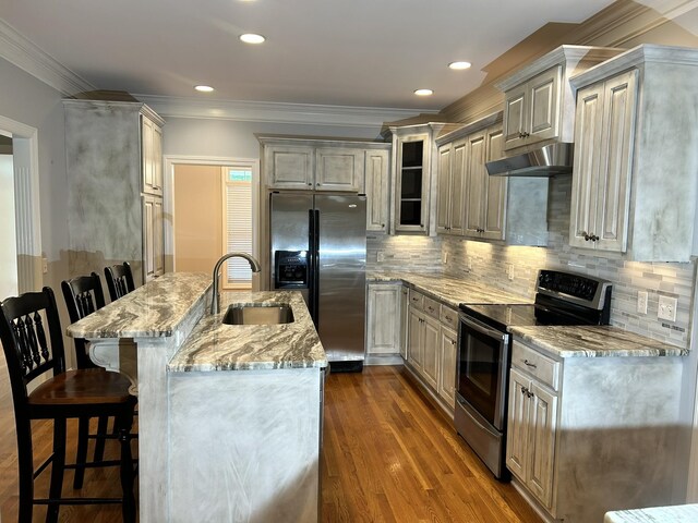 kitchen with stainless steel appliances, sink, decorative backsplash, dark hardwood / wood-style floors, and a kitchen breakfast bar