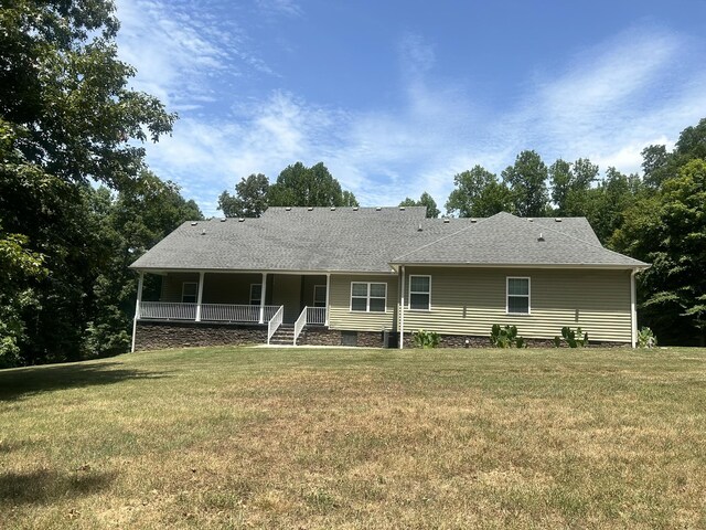 rear view of property featuring a porch and a lawn