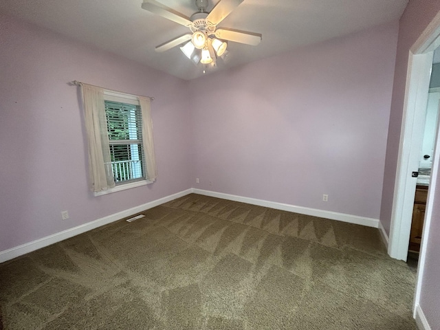unfurnished room with ceiling fan, dark colored carpet, visible vents, and baseboards