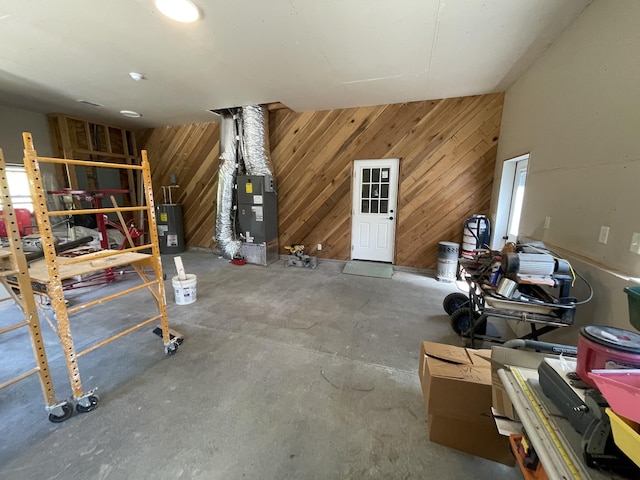 basement featuring heating unit, wood walls, and water heater