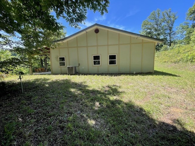 view of property exterior with a lawn and central AC