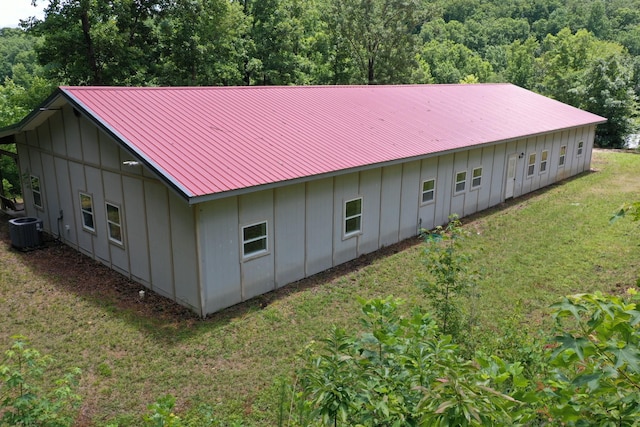 back of house featuring central AC unit and a lawn