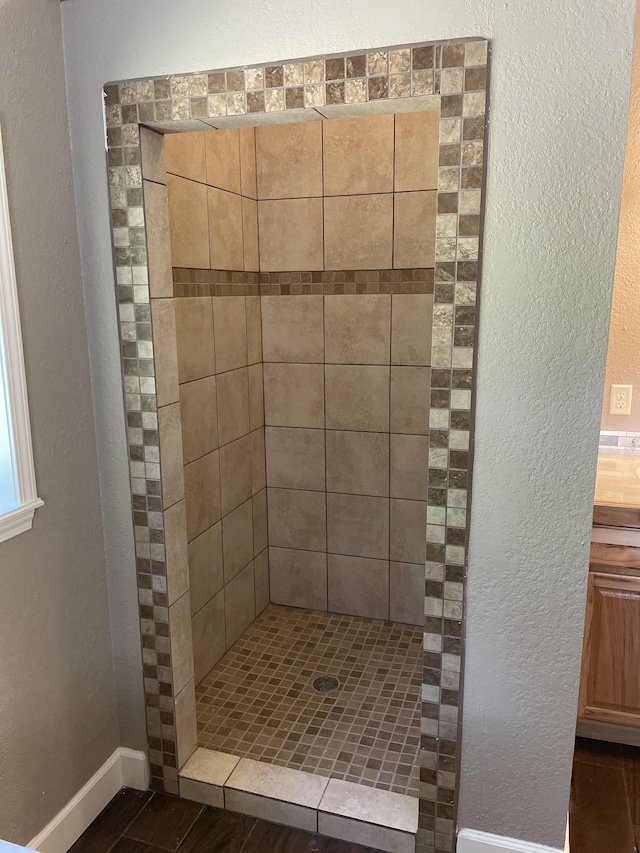 bathroom with a tile shower and vanity