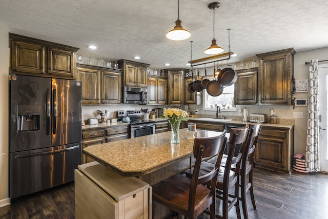 kitchen featuring a center island, appliances with stainless steel finishes, dark hardwood / wood-style flooring, and decorative light fixtures