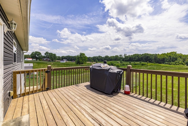 wooden deck featuring a yard and a grill