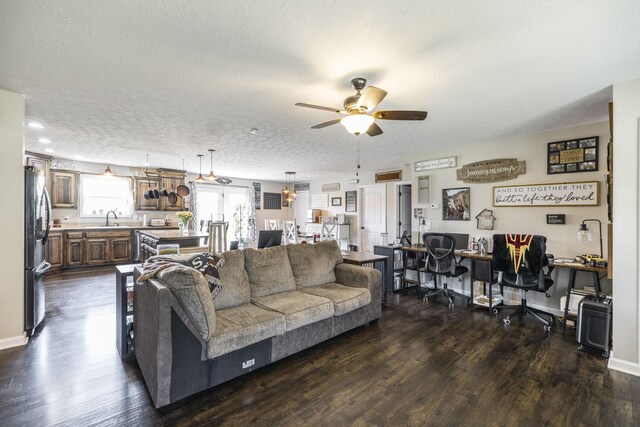 living room with sink, a textured ceiling, ceiling fan, and dark wood-type flooring