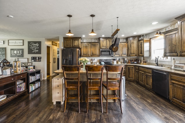 kitchen with appliances with stainless steel finishes, dark hardwood / wood-style flooring, a center island, and sink