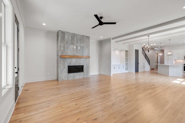 unfurnished living room featuring light hardwood / wood-style flooring, ceiling fan with notable chandelier, a fireplace, and ornamental molding