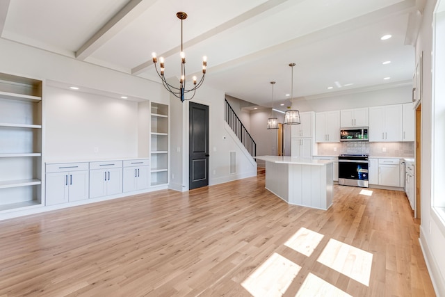 kitchen featuring a kitchen island, white cabinetry, hanging light fixtures, stainless steel appliances, and an inviting chandelier