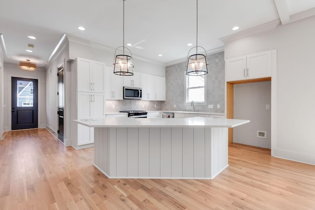 kitchen featuring white cabinetry, hanging light fixtures, appliances with stainless steel finishes, and a kitchen island