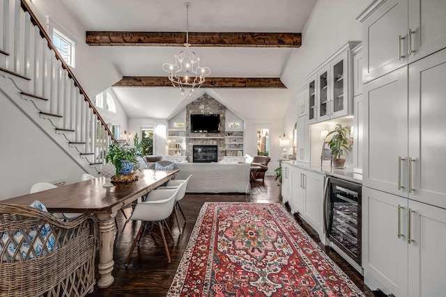 dining area with beverage cooler, a notable chandelier, beamed ceiling, a large fireplace, and dark hardwood / wood-style flooring