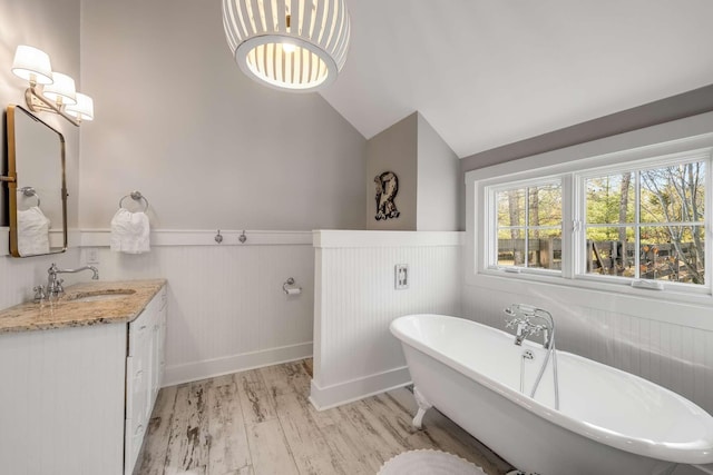 bathroom with hardwood / wood-style flooring, lofted ceiling, a bathtub, and vanity