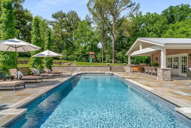 view of swimming pool featuring a patio area, an outbuilding, a bar, and a playground