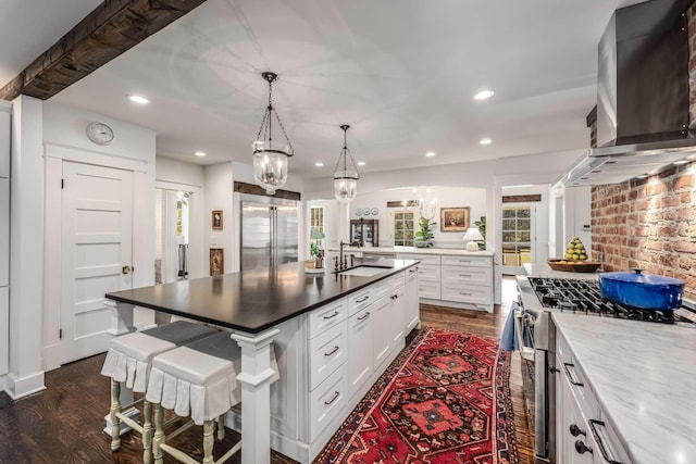 kitchen featuring sink, appliances with stainless steel finishes, white cabinets, a breakfast bar area, and pendant lighting