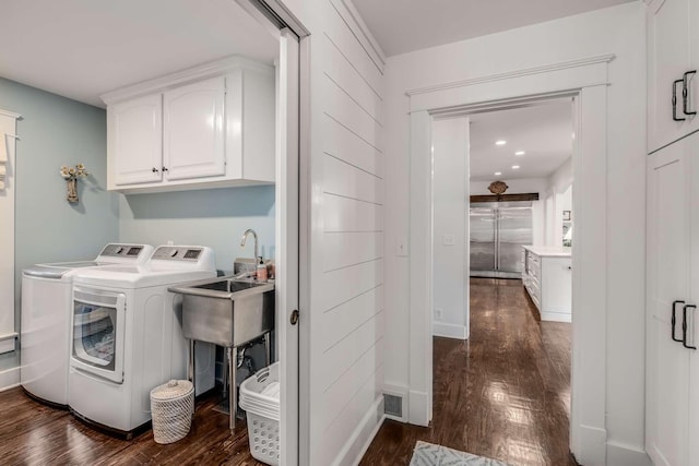 washroom featuring washing machine and dryer, cabinets, sink, and dark hardwood / wood-style floors