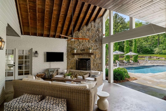 exterior space with beam ceiling, brick wall, an outdoor stone fireplace, wooden ceiling, and high vaulted ceiling